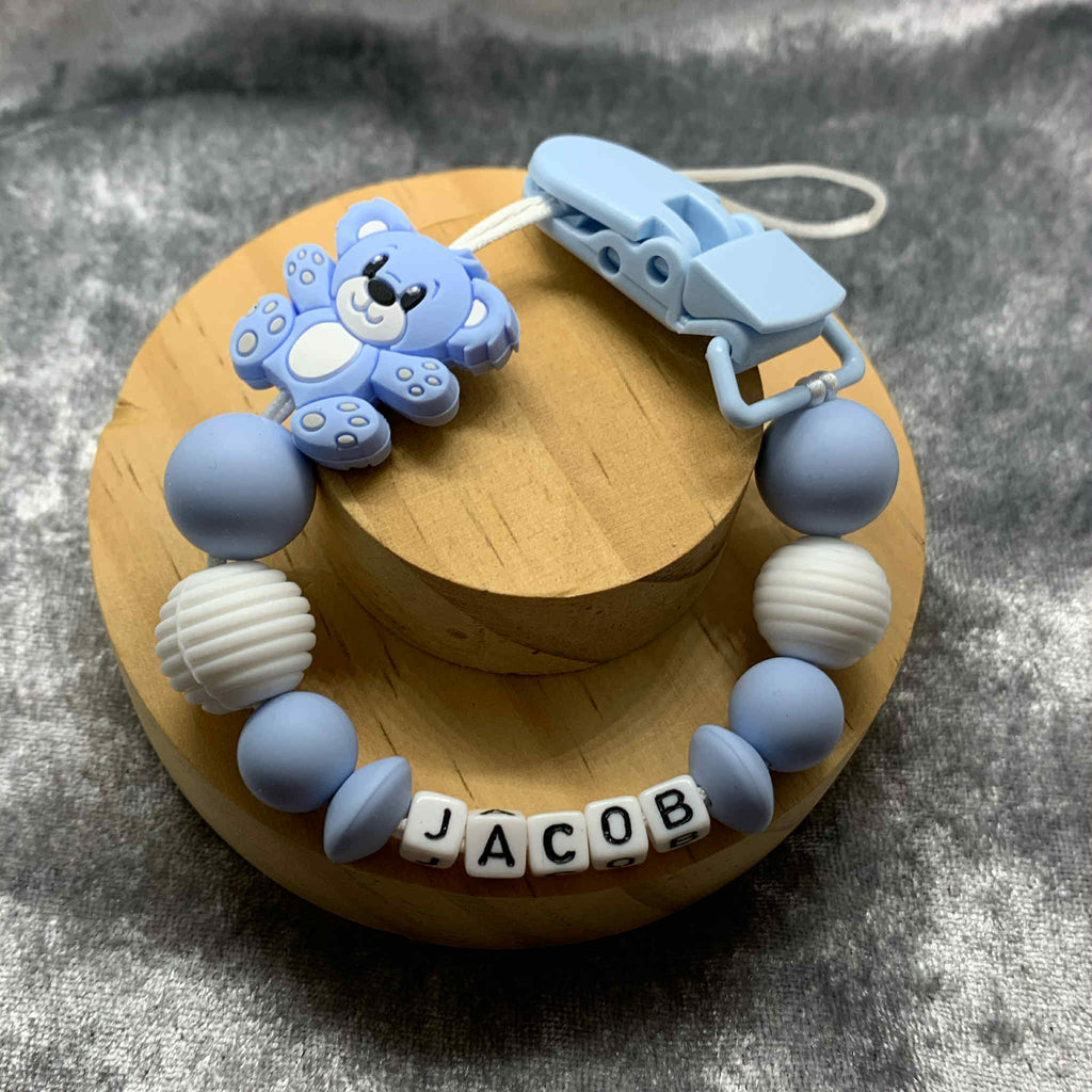 Blue and white teddybear dummy chain on a grey textured surface personalised with the name 'Jacob'. Personalisation and MAM Adapter options available.