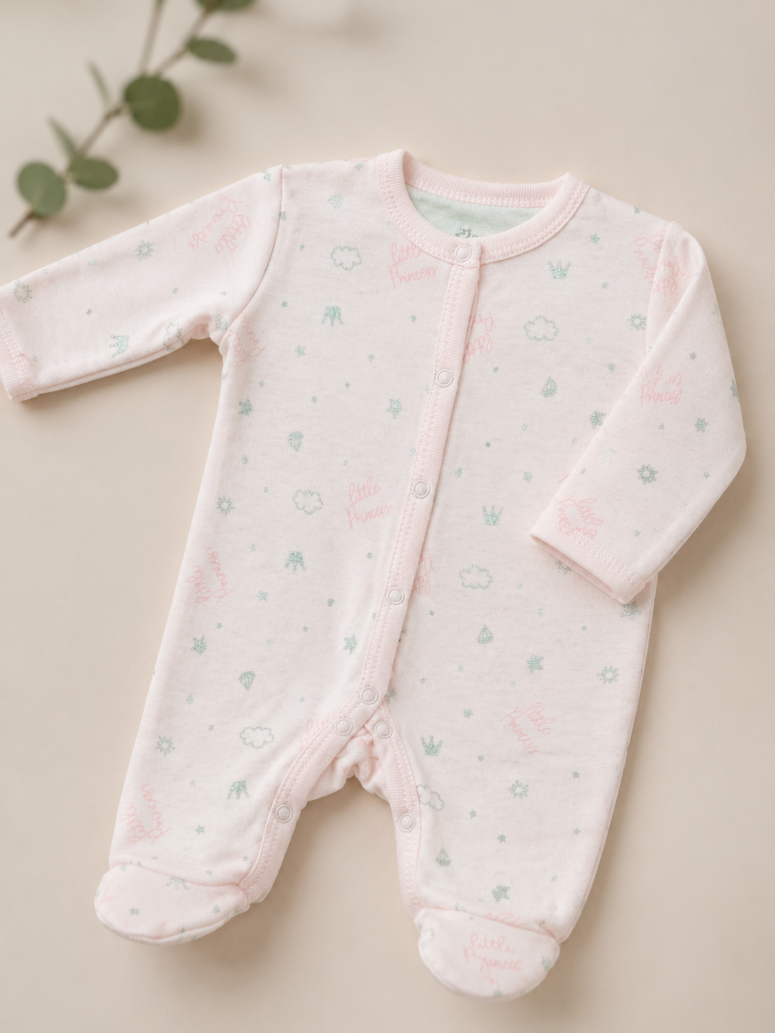 Pink baby onesie with subtle pattern on a beige background