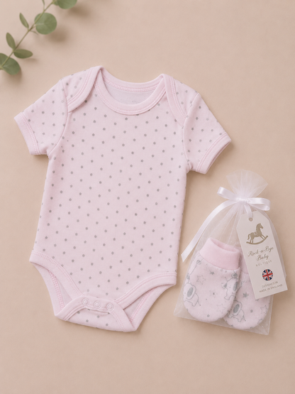 Pink baby bodysuit with star pattern and matching mittens on a beige background