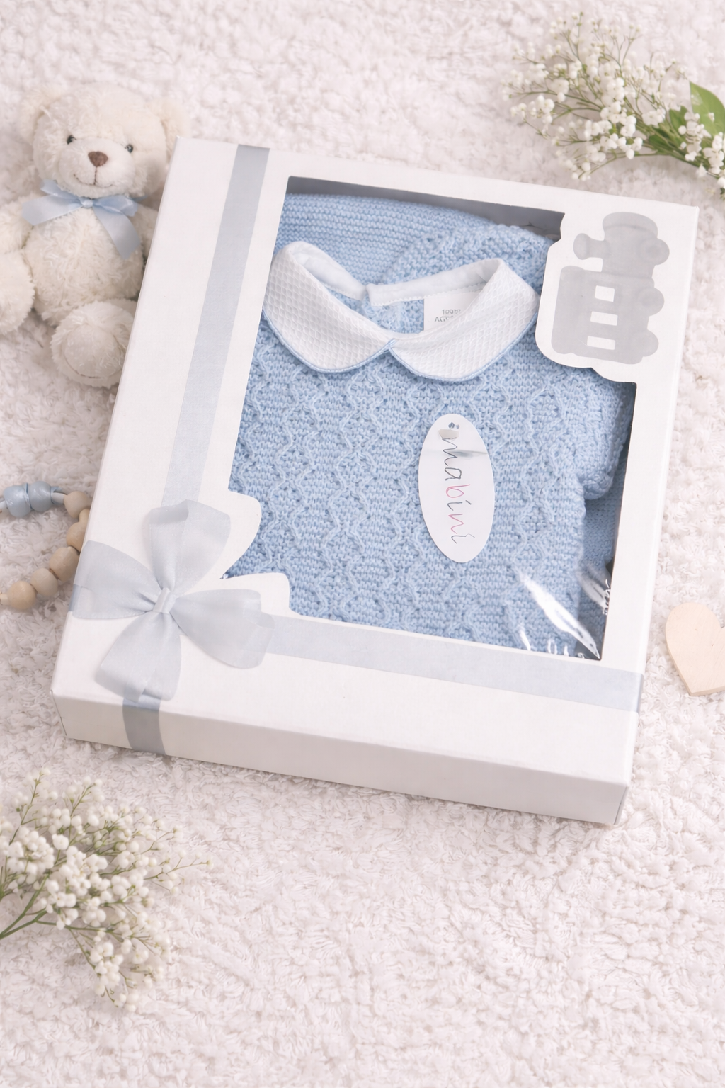 Baby shower gift set with blue baby blanket, white booties, and a teddy bear in a decorative box.