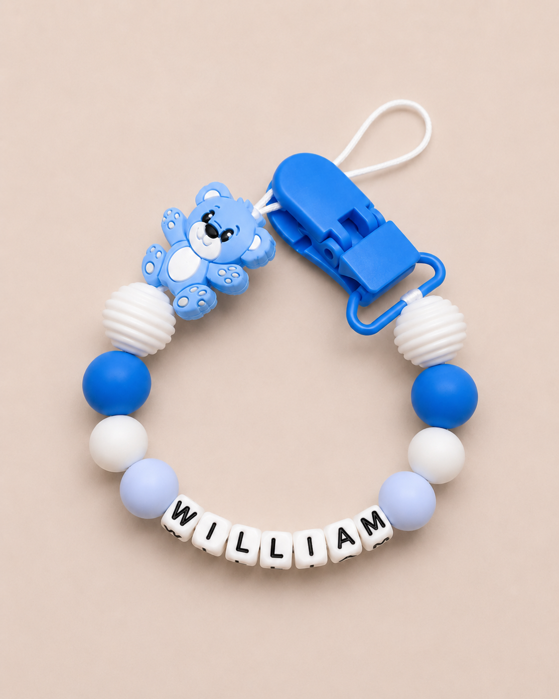 Baby dummy clip with blue and white beads and a clip on a beige background