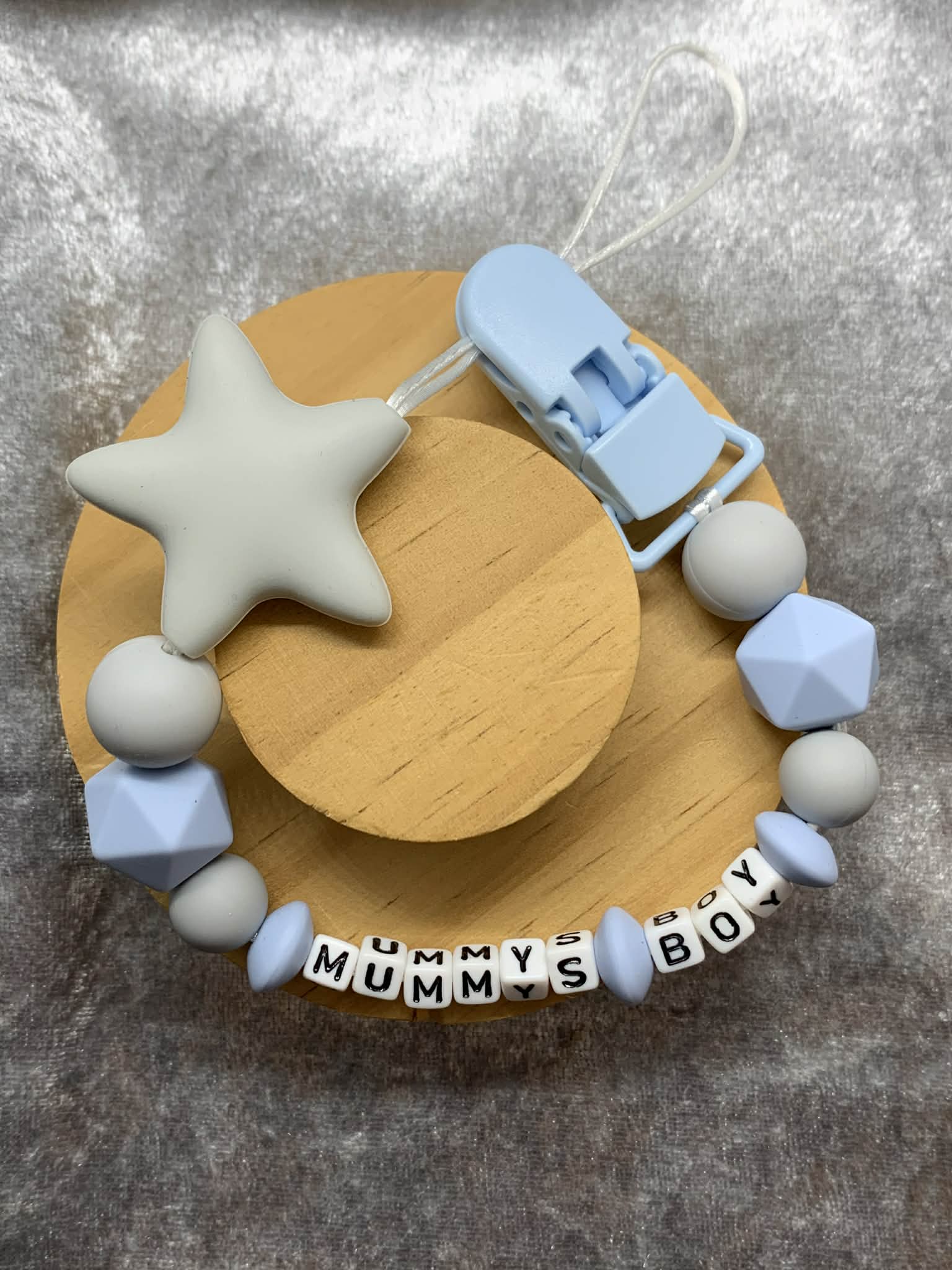 Grey and blue Silicone Dummy Clip personalised with the name 'Grayson' on a grey textured surface. Can be personalised