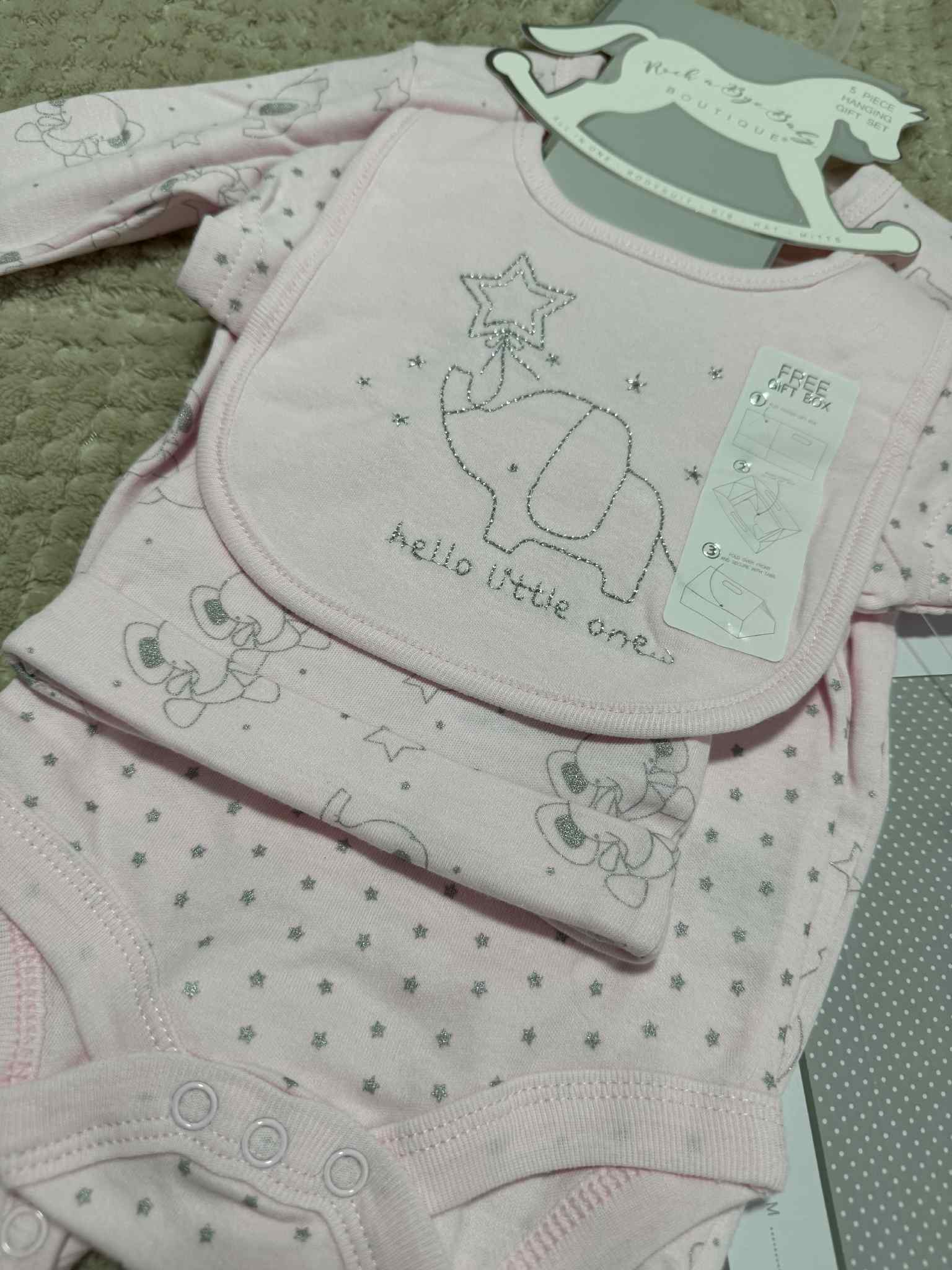 Baby clothing set with onesie, bib, and pants on a green surface