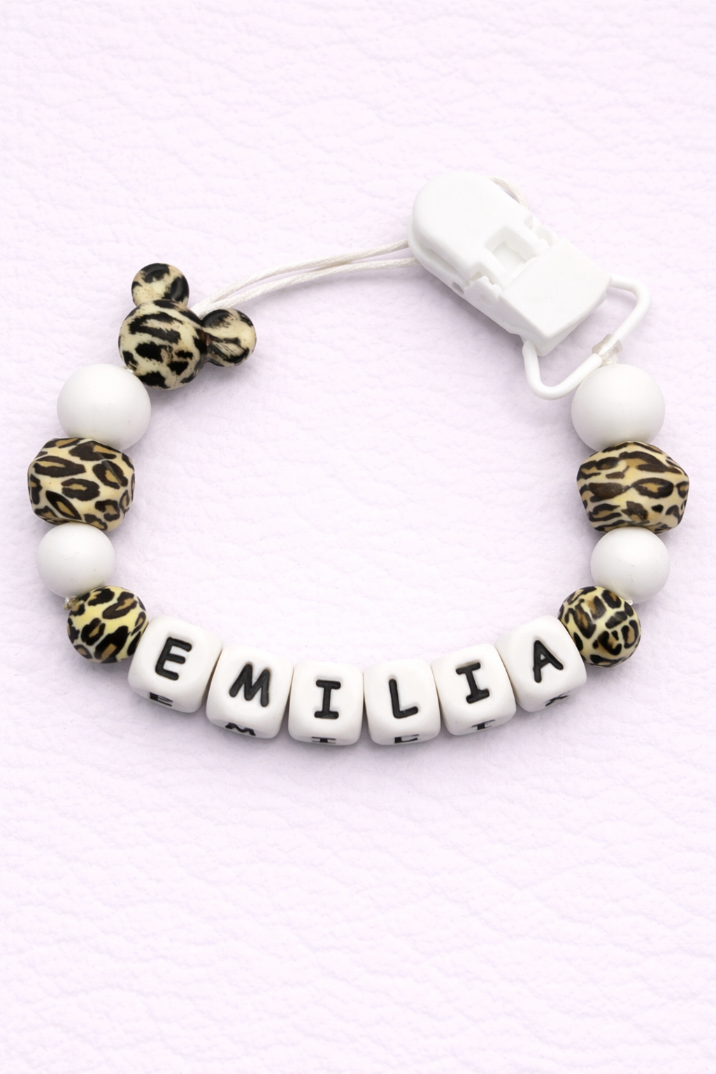 dummy clip with letter beads spelling 'EMILIA' on a light pink background