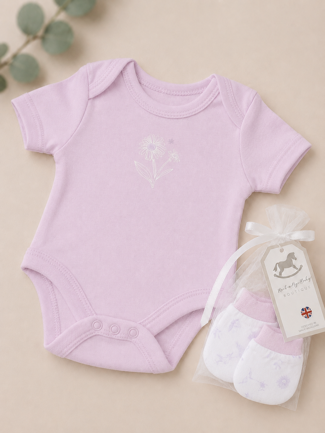Baby onesie and socks set with a tag on a beige background