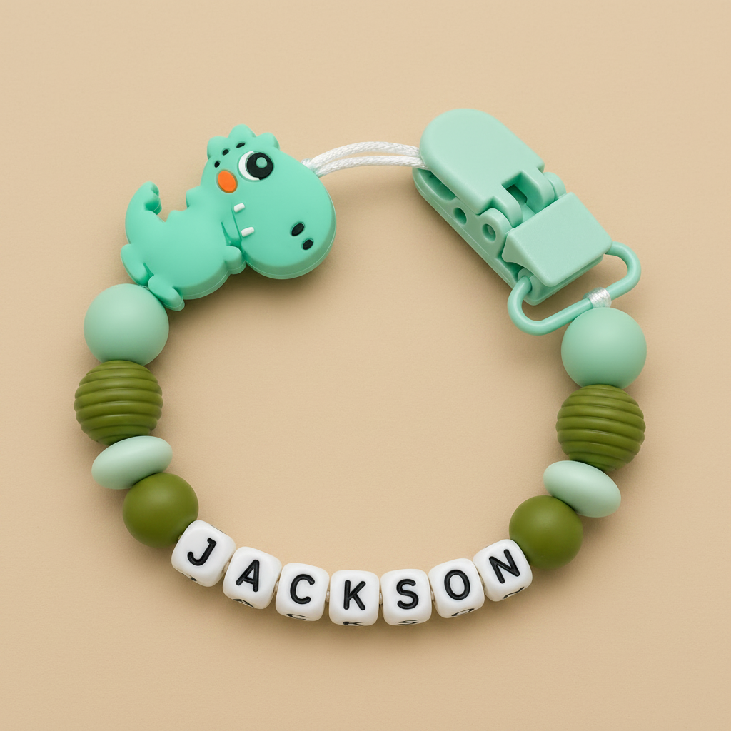 dummy clip with dinosaur design and 'JACKSON' name on a beige background