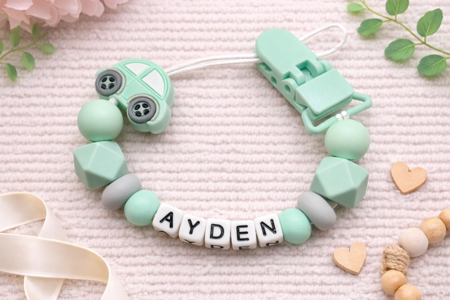 mint green personalised car pacifier clip with customizable name on a soft pink background