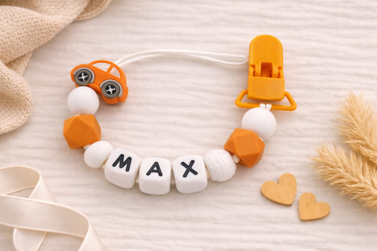 orange silicone dummy clip with 'MAX' name beads on a soft surface