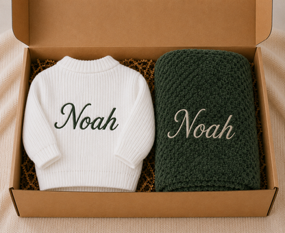 White sweater and green blanket with 'Noah' embroidered on a brown box.