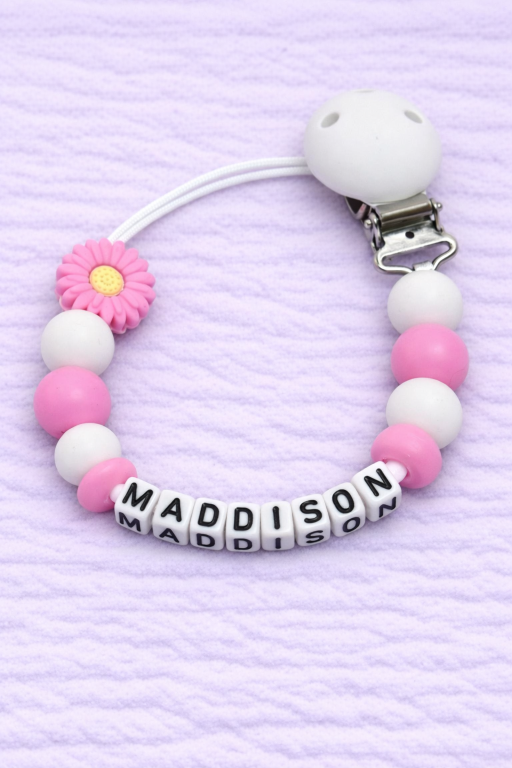 Beaded pacifier clip with 'MADDISON' on a purple textured background
