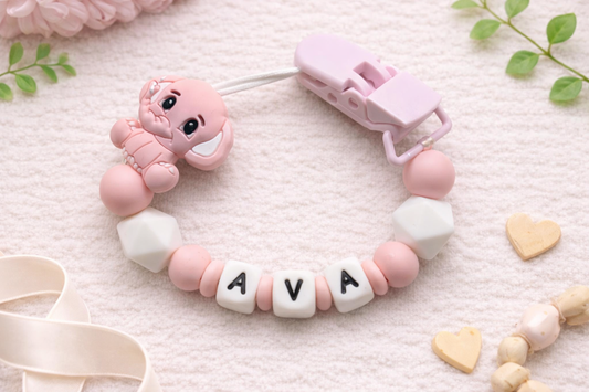 pink elephant silicone dummy clip with 'AVA' beads on a light background