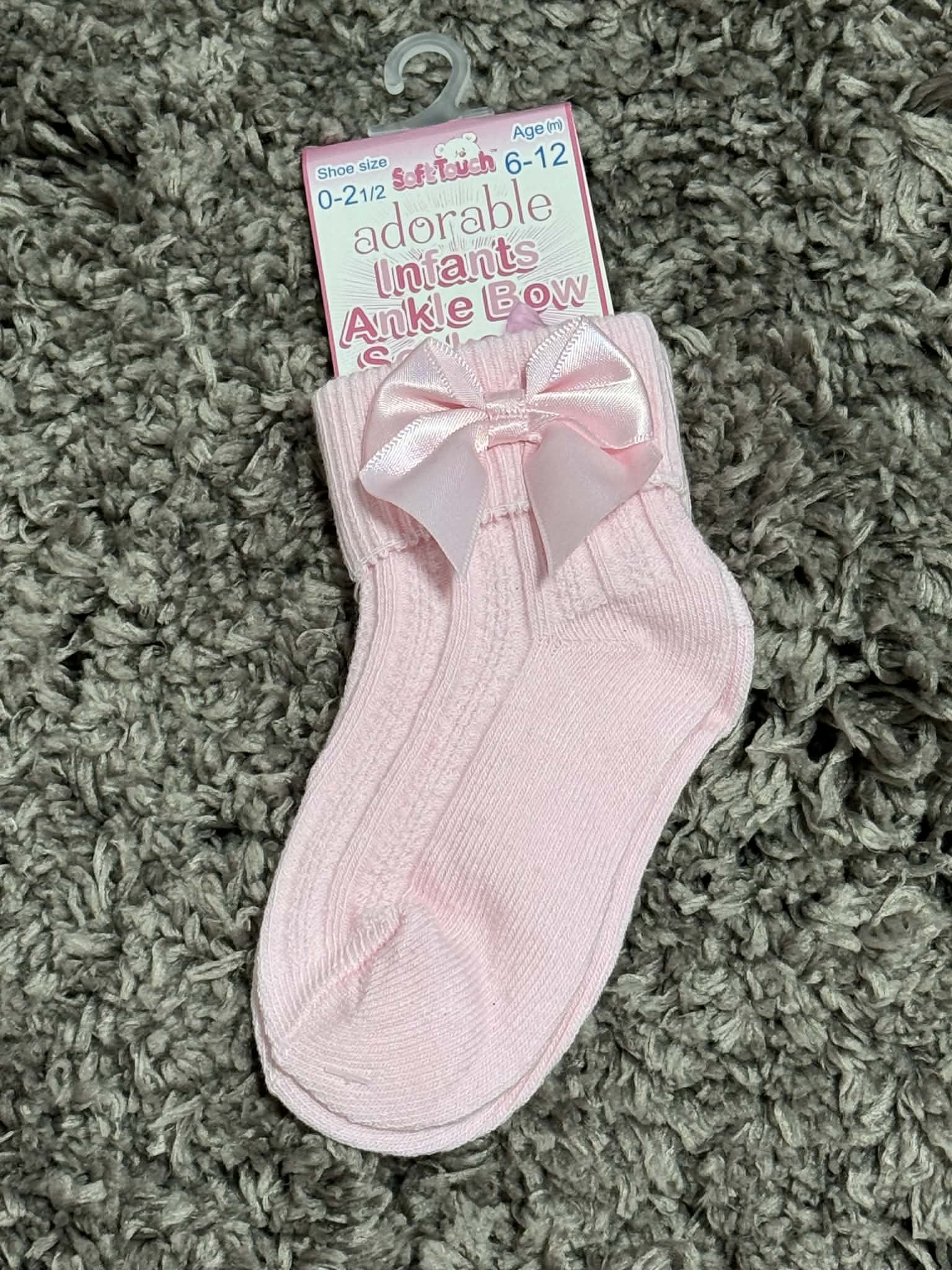 Pink ankle sock with bow on a green carpet