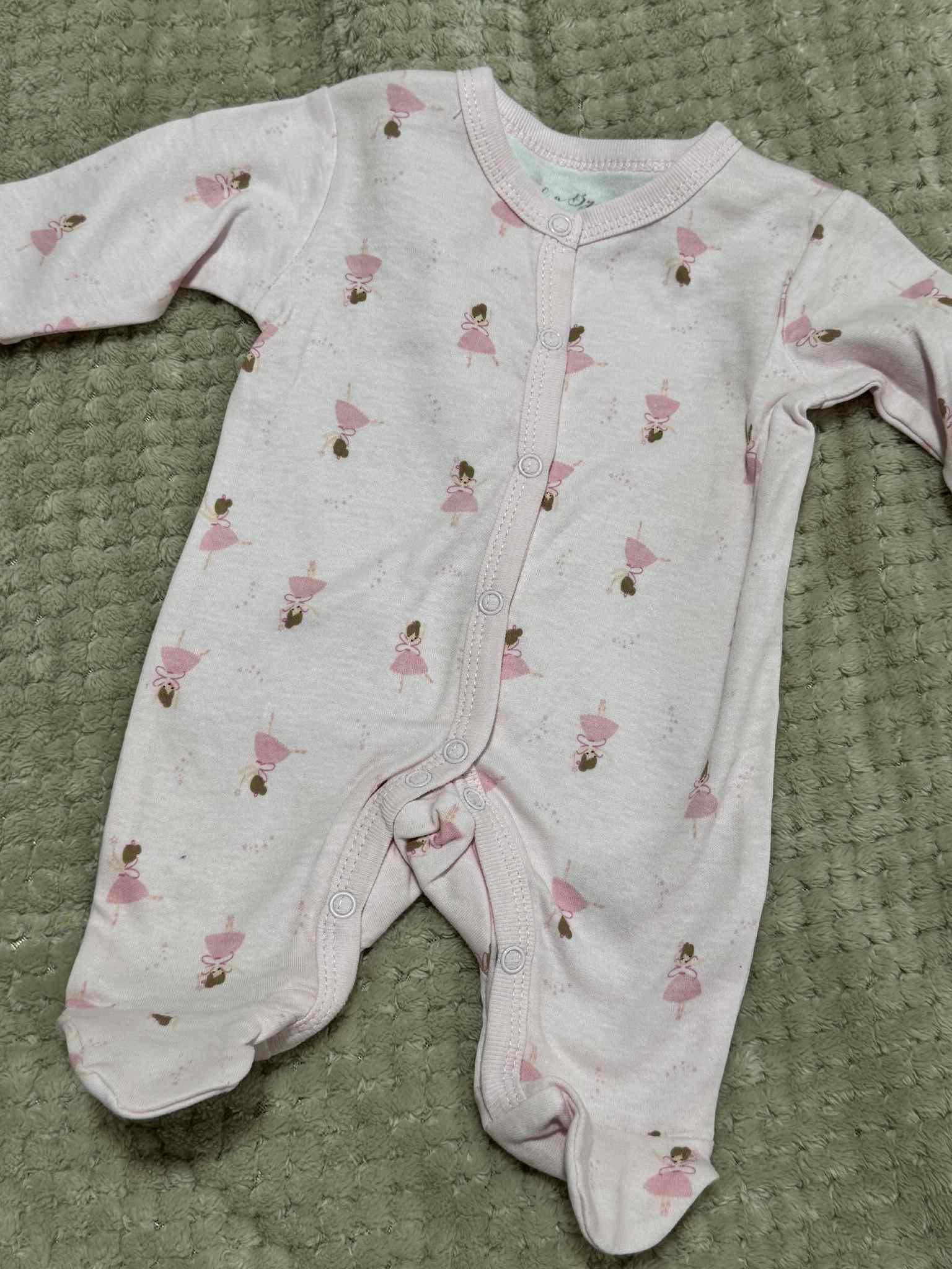 Baby onesie with pink designs on a textured green surface