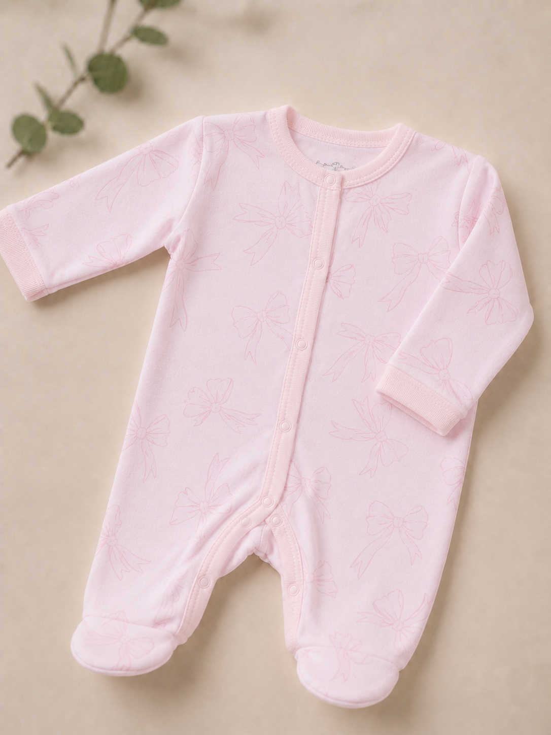 Pink baby onesie on a beige background