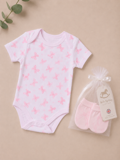 Baby onesie with pink butterfly pattern and matching socks on a beige background