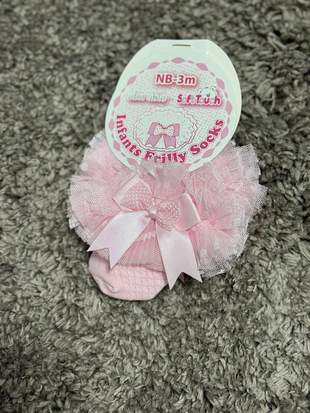 Pink frilly socks with a label on a textured surface
