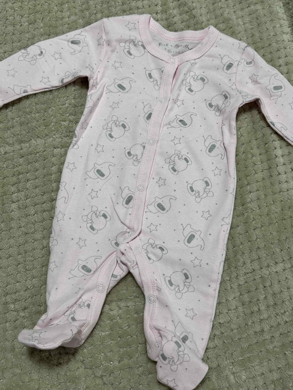 Baby onesie with elephant print on a textured green surface