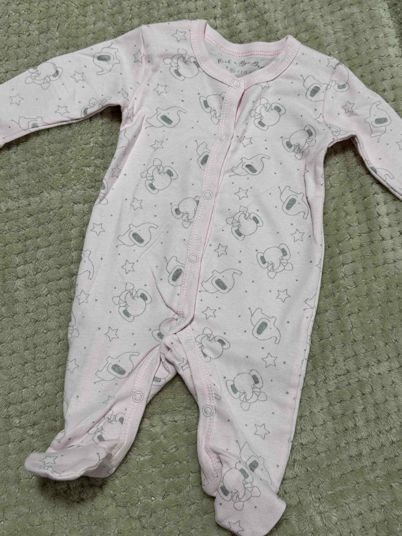 Baby onesie with elephant print on a textured green surface