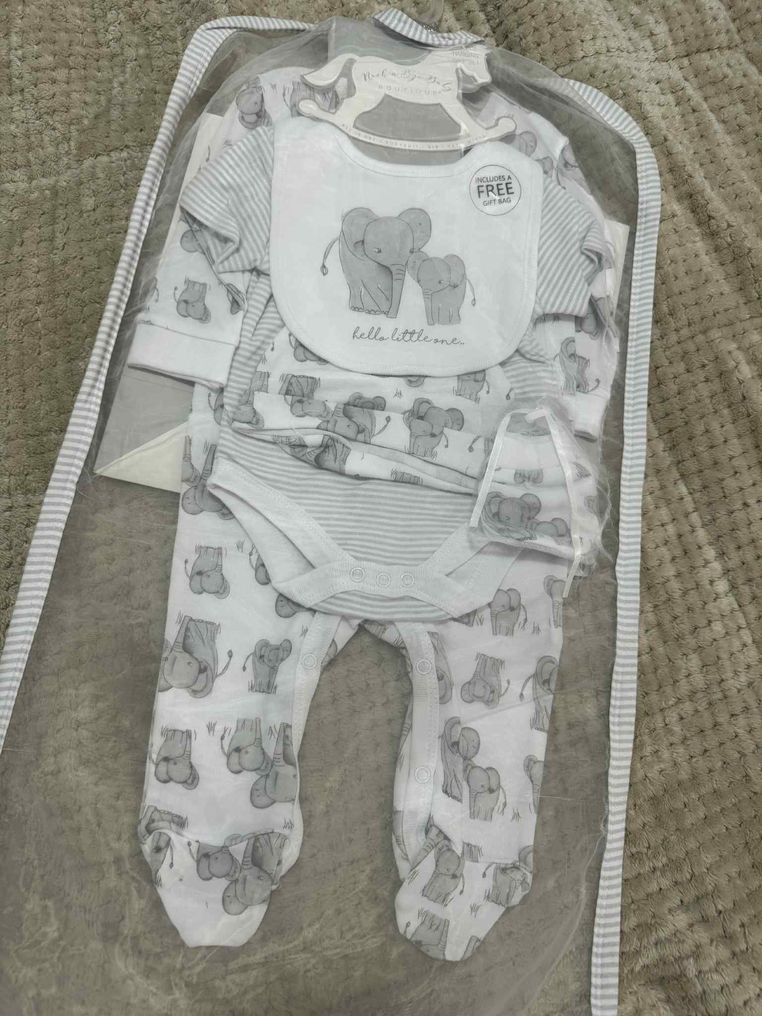Baby clothing set with romper, bib, and pants on a textured surface