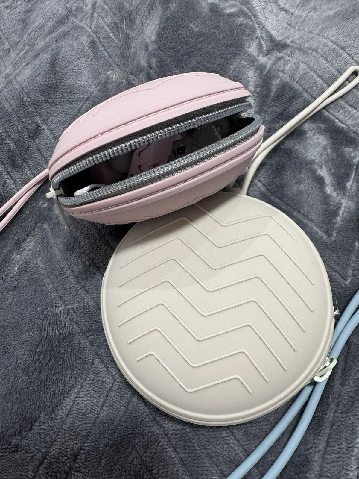 Two round pouches, one pink and one beige with a zigzag pattern, on a textured surface. for carrying and keeping dummy clips sterile