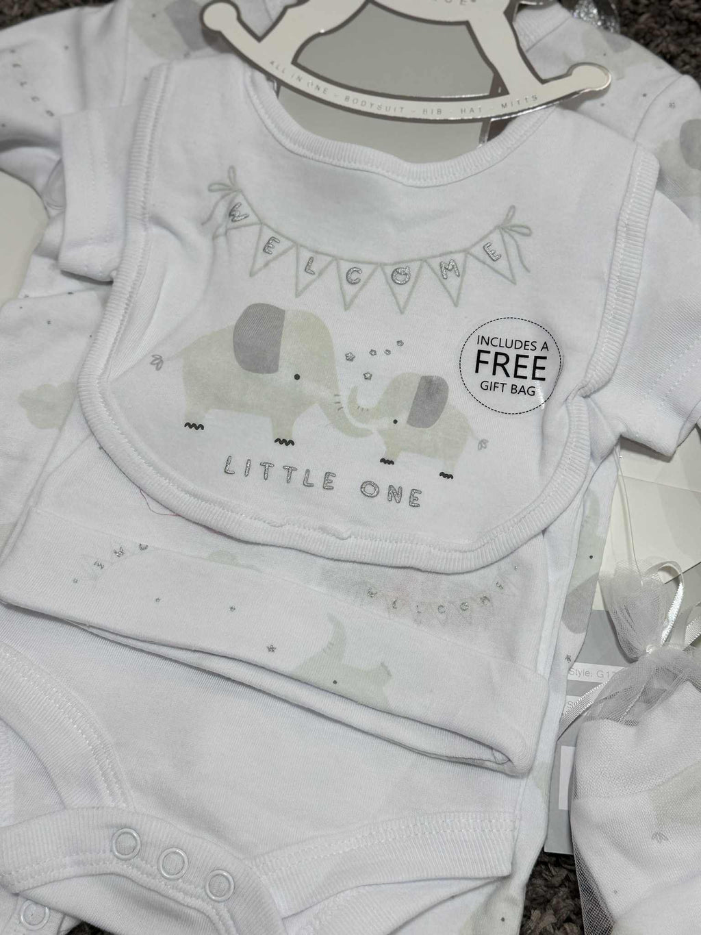 Baby clothing set with bib, onesie, and headband featuring elephant graphics on a hanger.