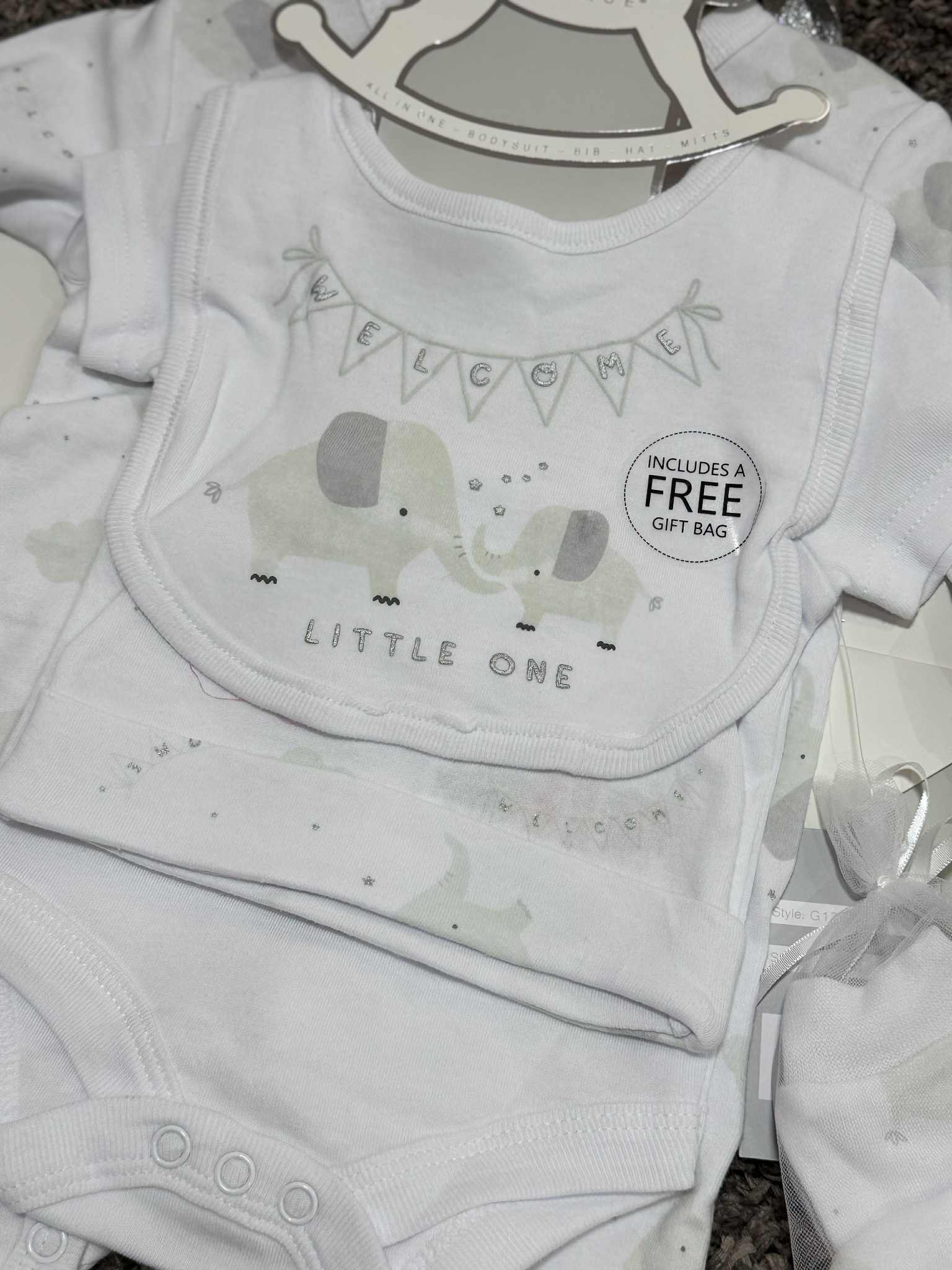 Baby clothing set with bib, onesie, and headband featuring elephant graphics on a hanger.