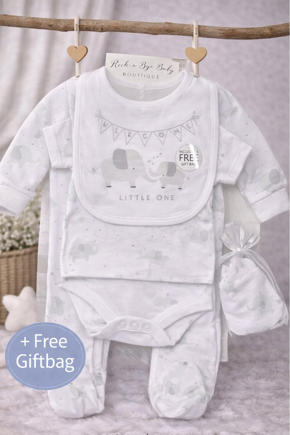 Baby gift set with onesie, bib, and booties on a wooden stick against a neutral background.