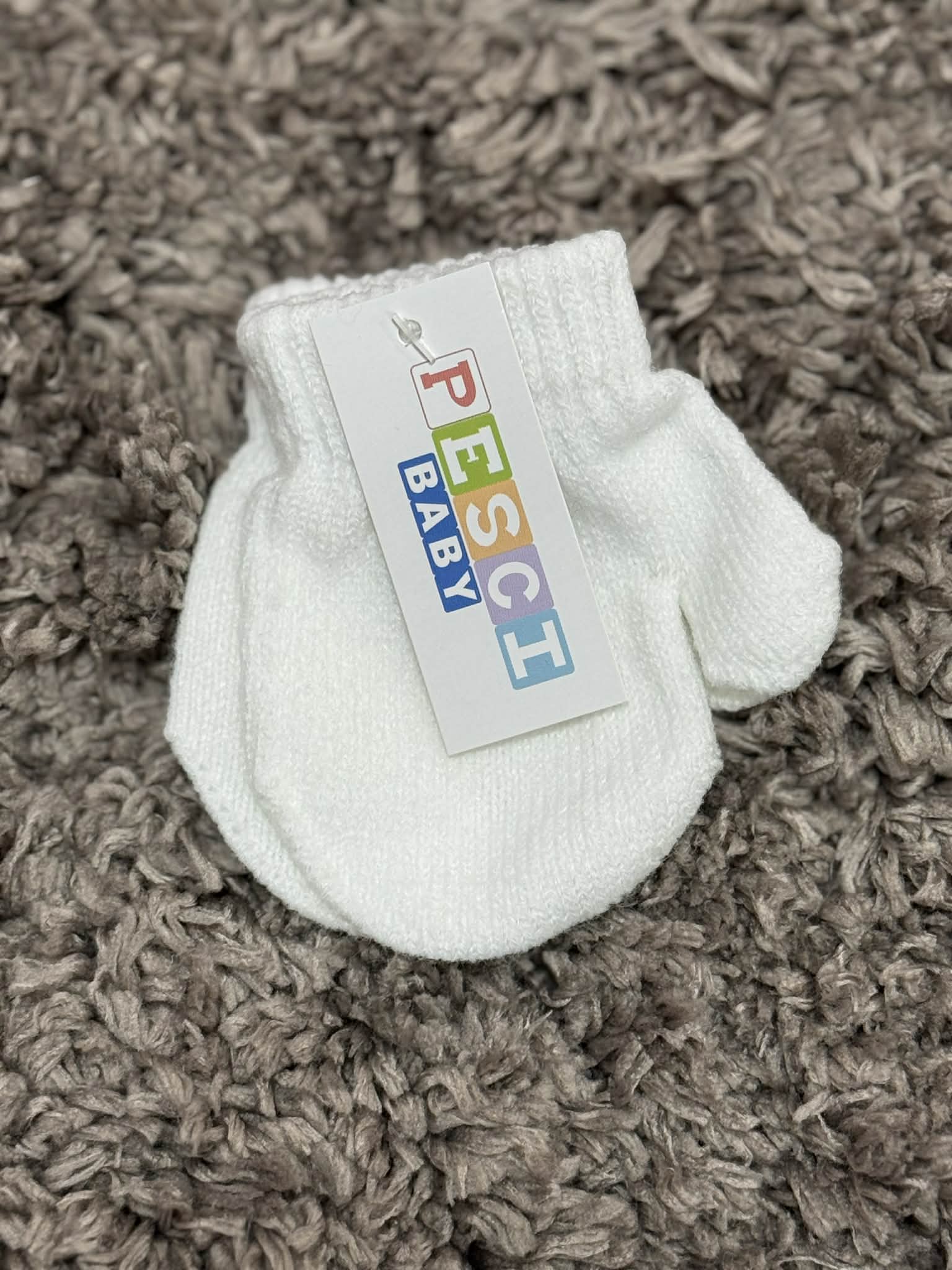 White baby bootie with a colorful label on a brown textured surface
