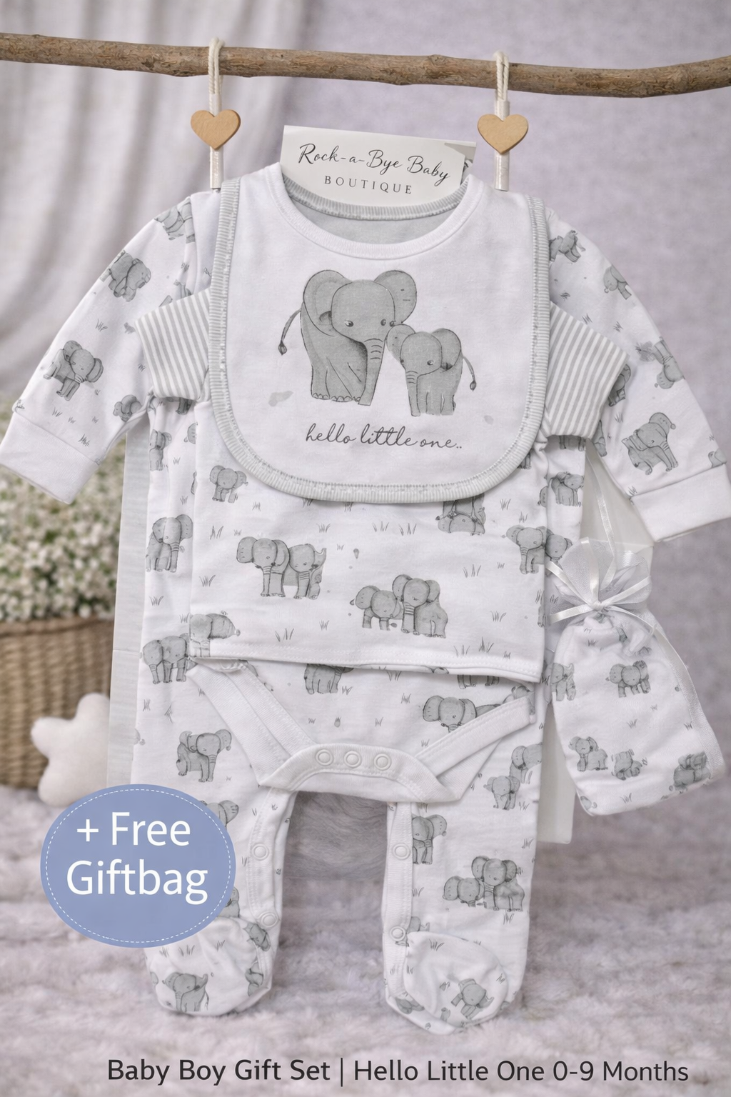 Baby boy gift set with bib, shirt, pants, and hat featuring elephant design on a neutral background.