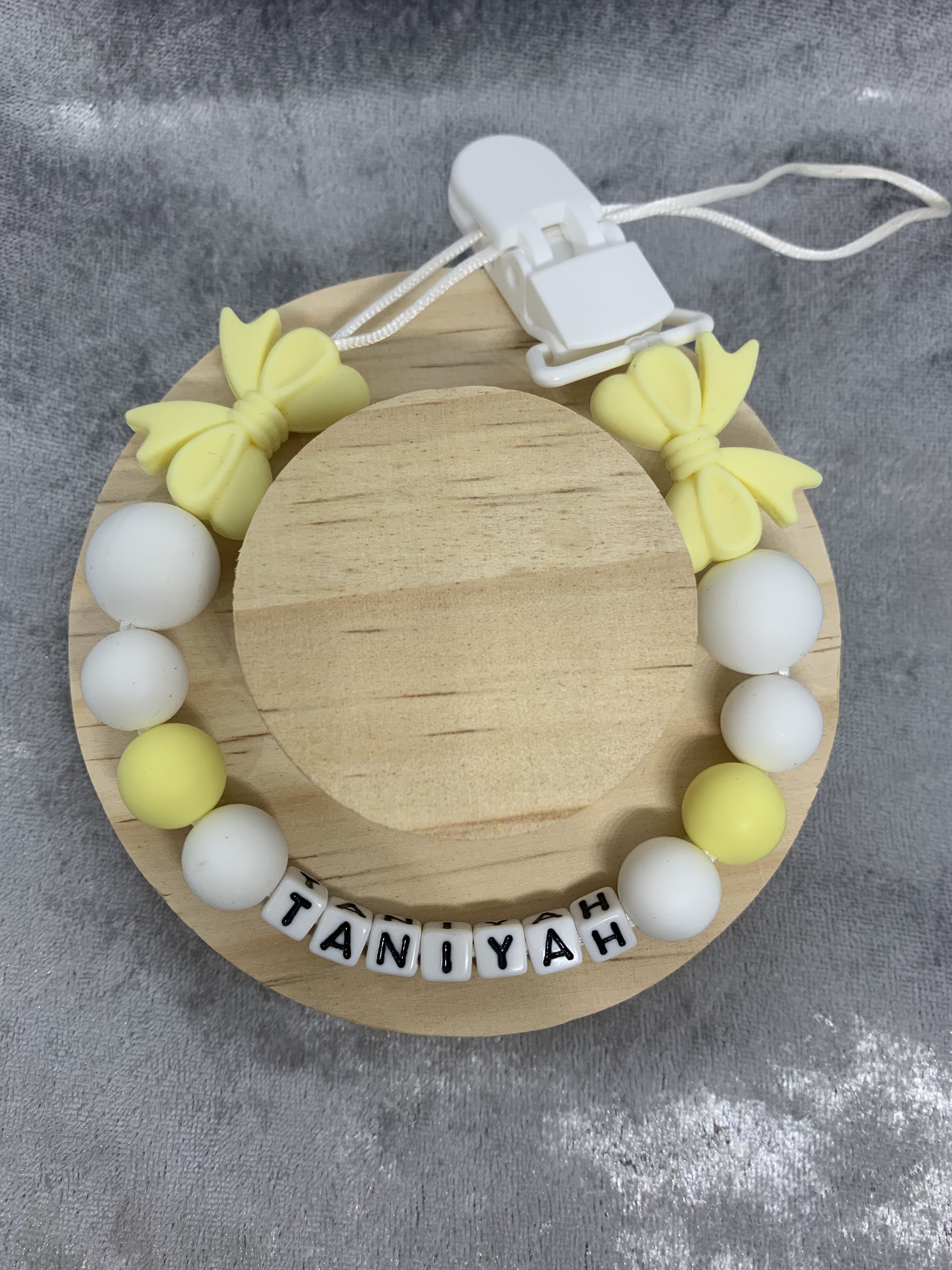 dummy chain with bow and with yellow and white beads and a name tag on a gray background